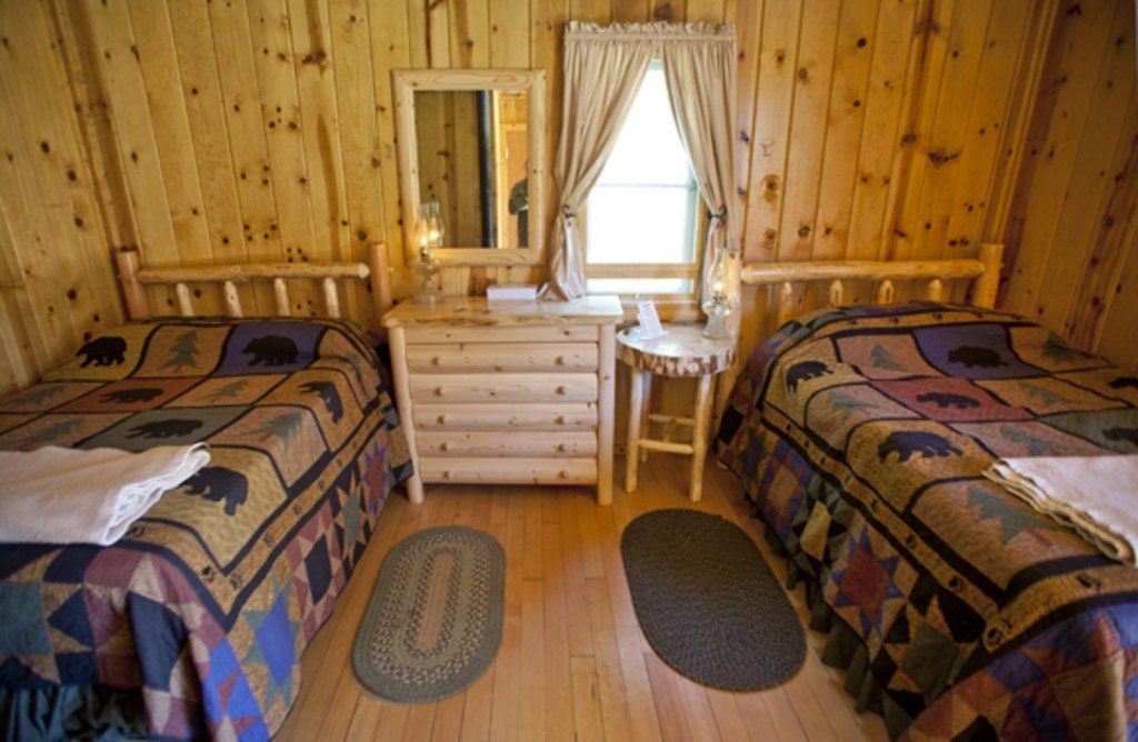 Cosy guest room lined with knotty pine boards and patchwork quilts