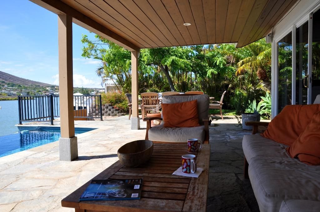 Shaded covered patio with deep sofas beside a swimming pool